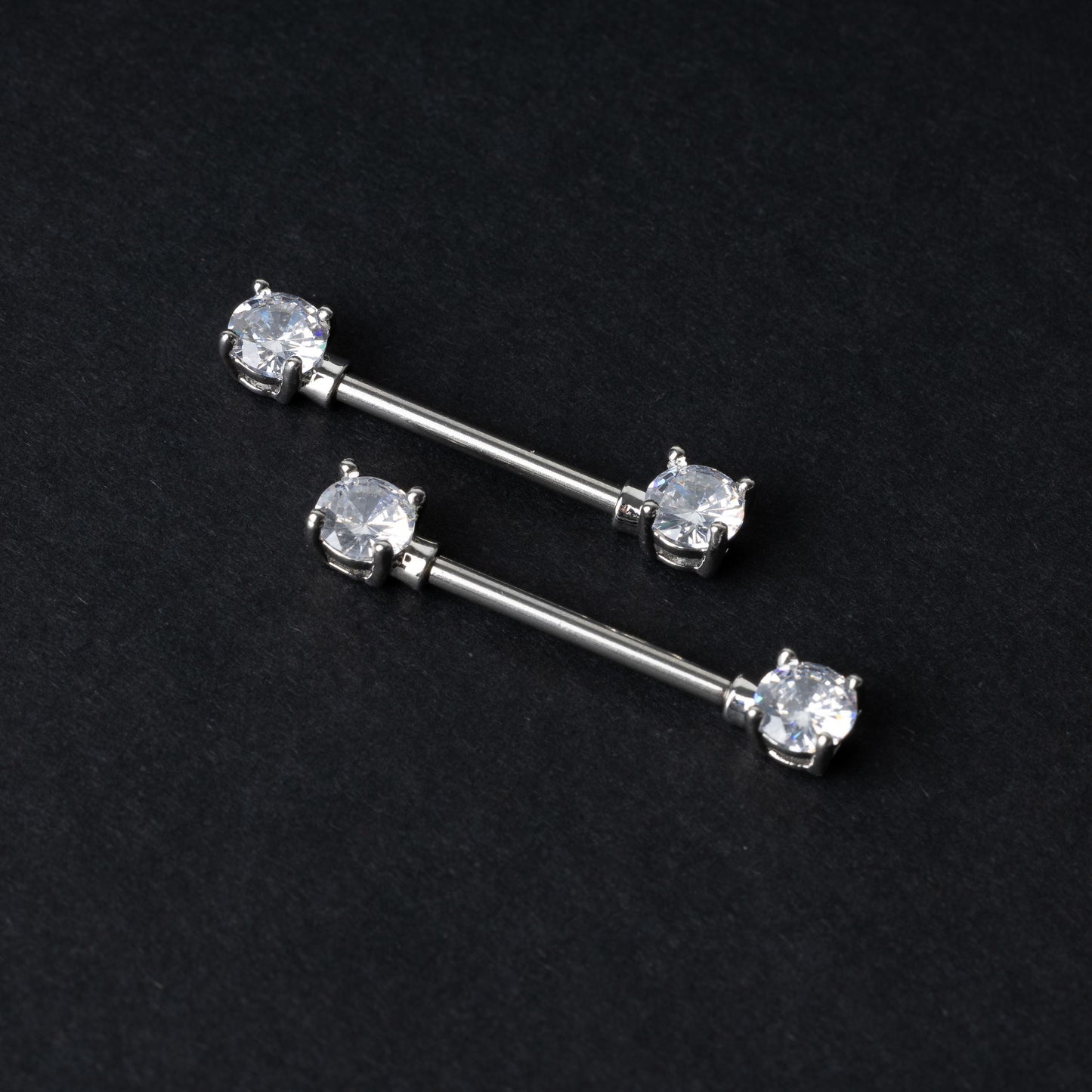 Crystal-studded barbells in silver displayed on a dark background.