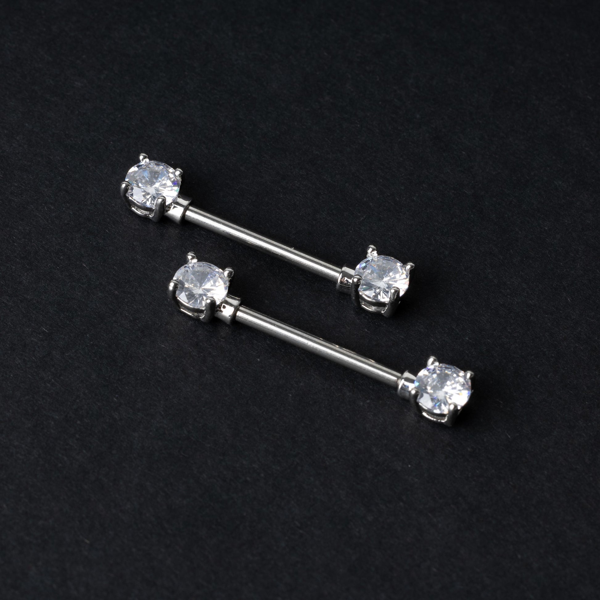 Crystal-studded barbells in silver displayed on a dark background.