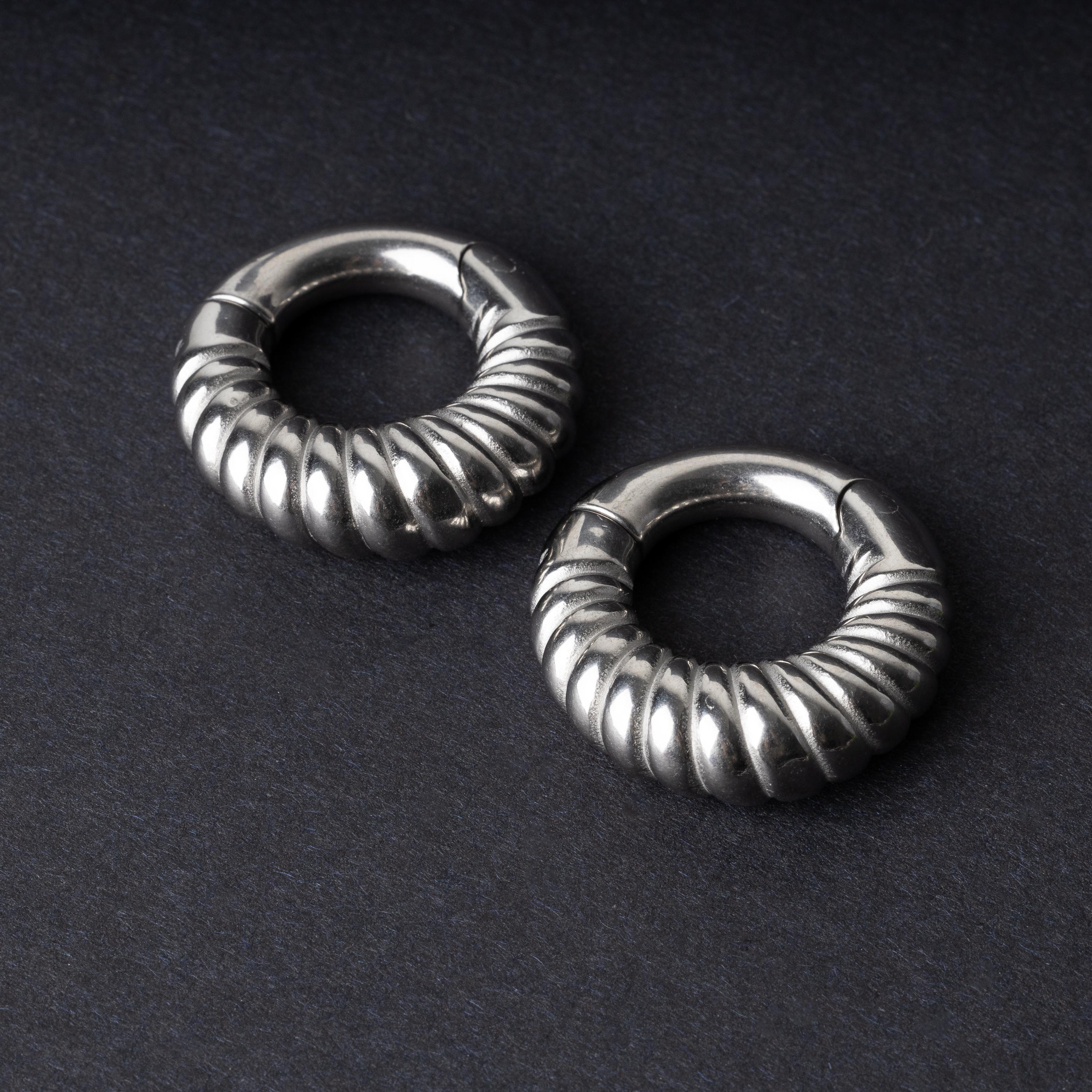 Silver textured hoop rings with a ridged design on a dark background.