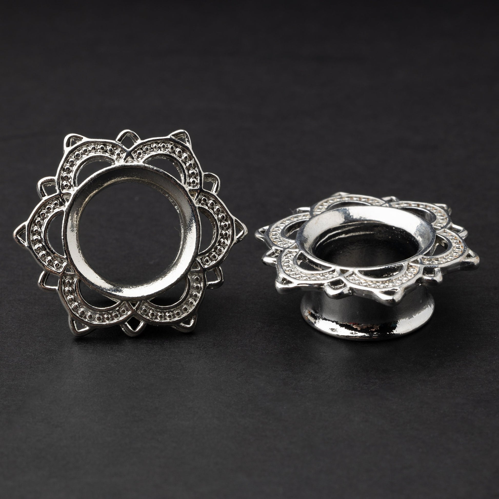 Silver flower-shaped tunnels with intricate detailing, displayed on a dark background.