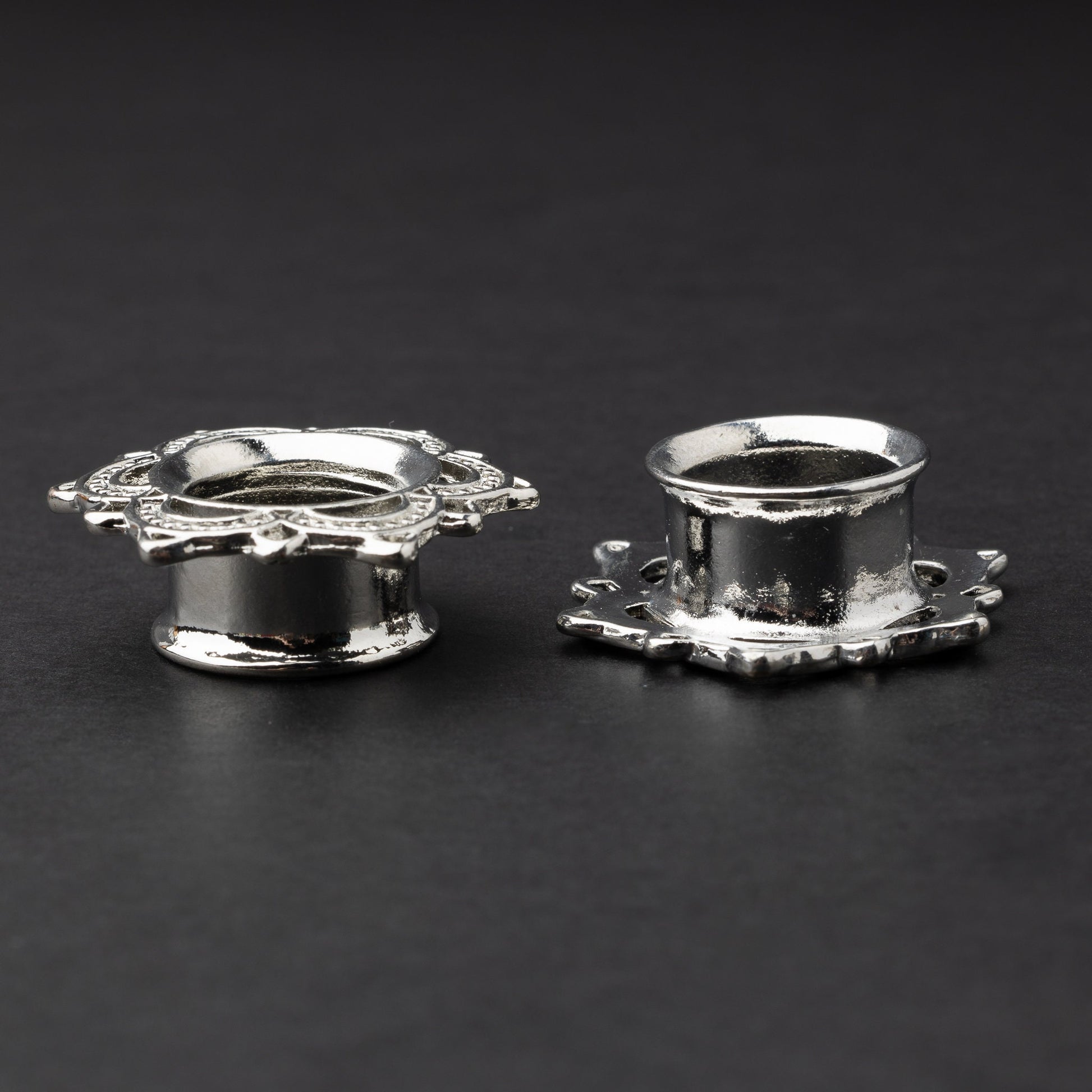 Silver flower-shaped tunnels with intricate detailing, displayed on a dark background.
