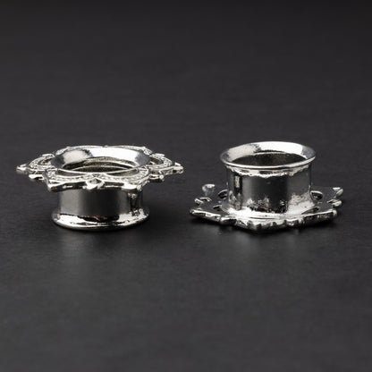 Silver flower-shaped tunnels with intricate detailing, displayed on a dark background.