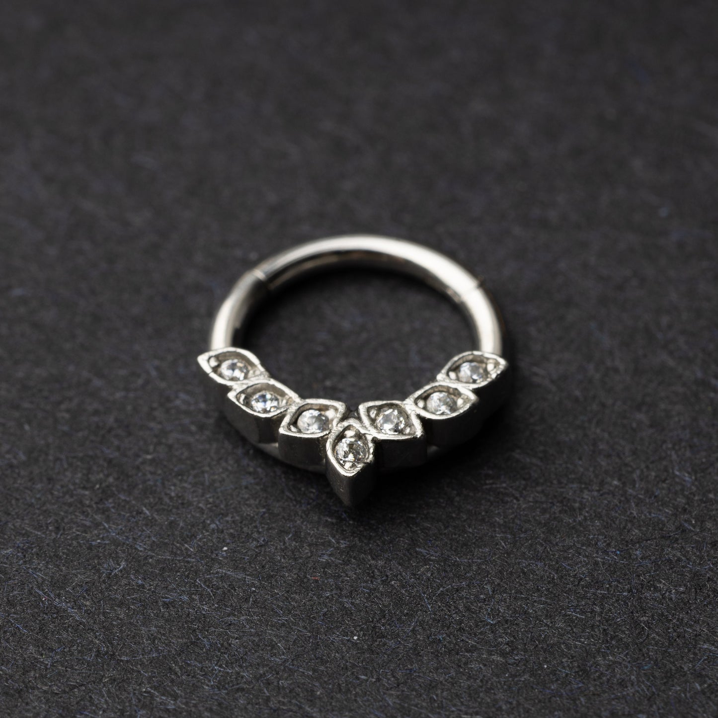 Marquise gemstone stainless steel clicker in silver displayed on a dark textured background.