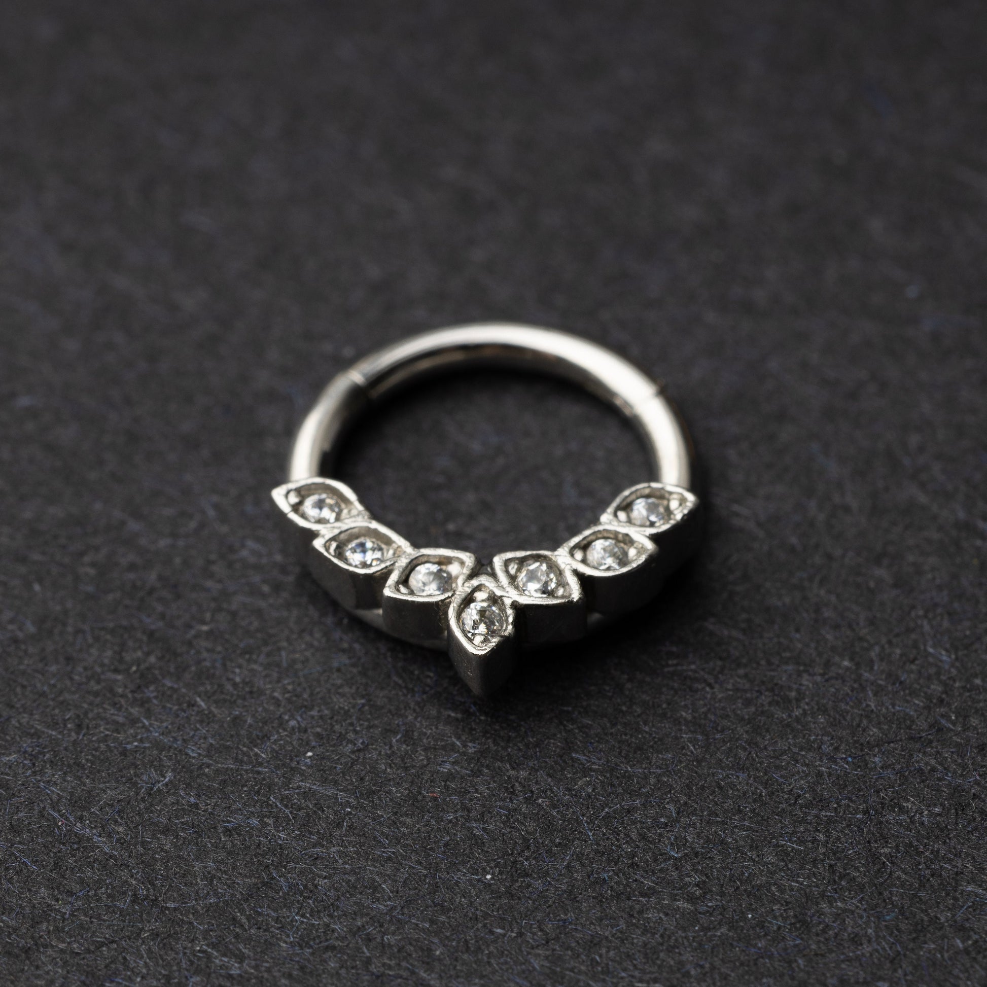Marquise gemstone stainless steel clicker in silver displayed on a dark textured background.
