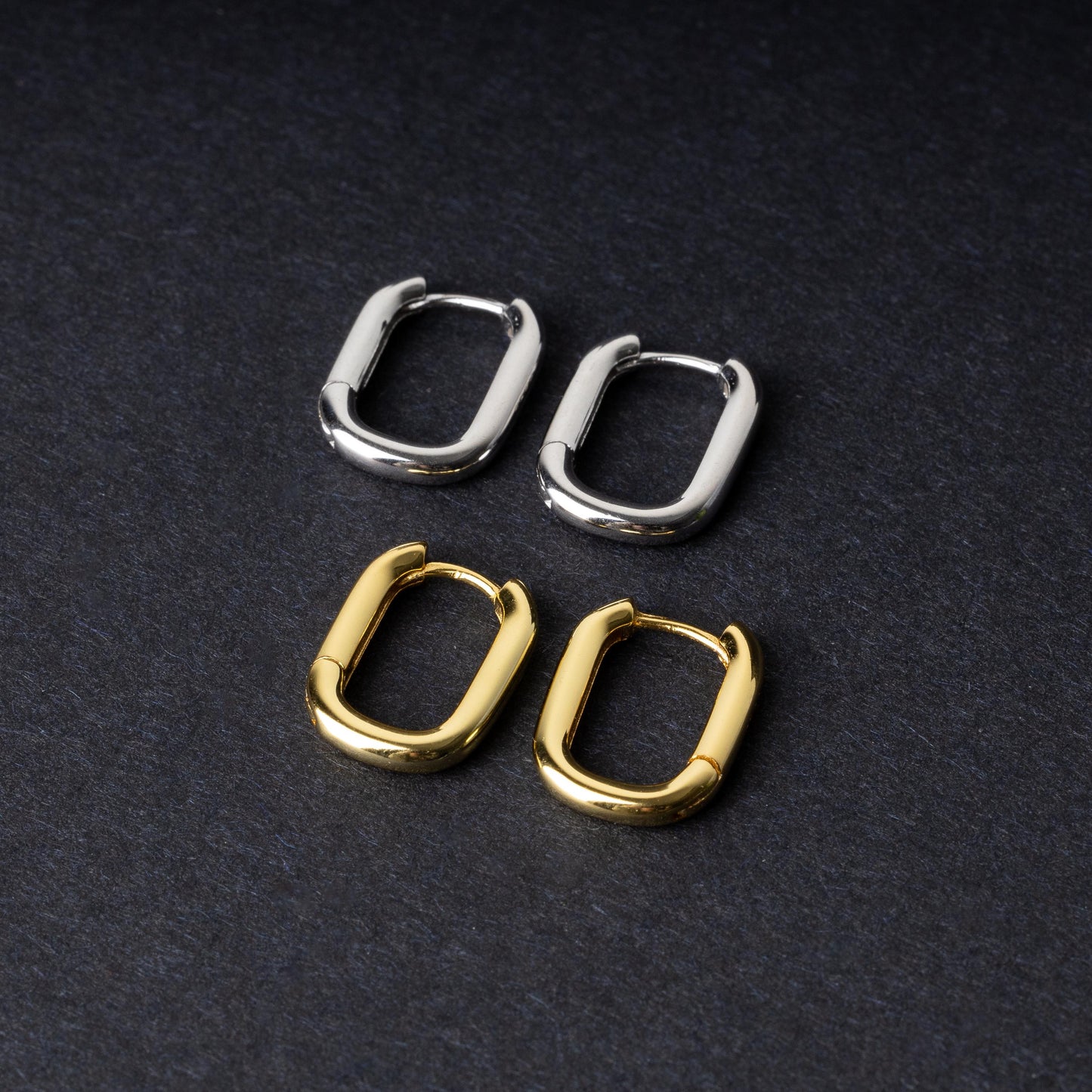 Four rectangular huggie hoop earrings made from 925 sterling silver, two in gold-tone and two in silver-tone, displayed on a dark background.