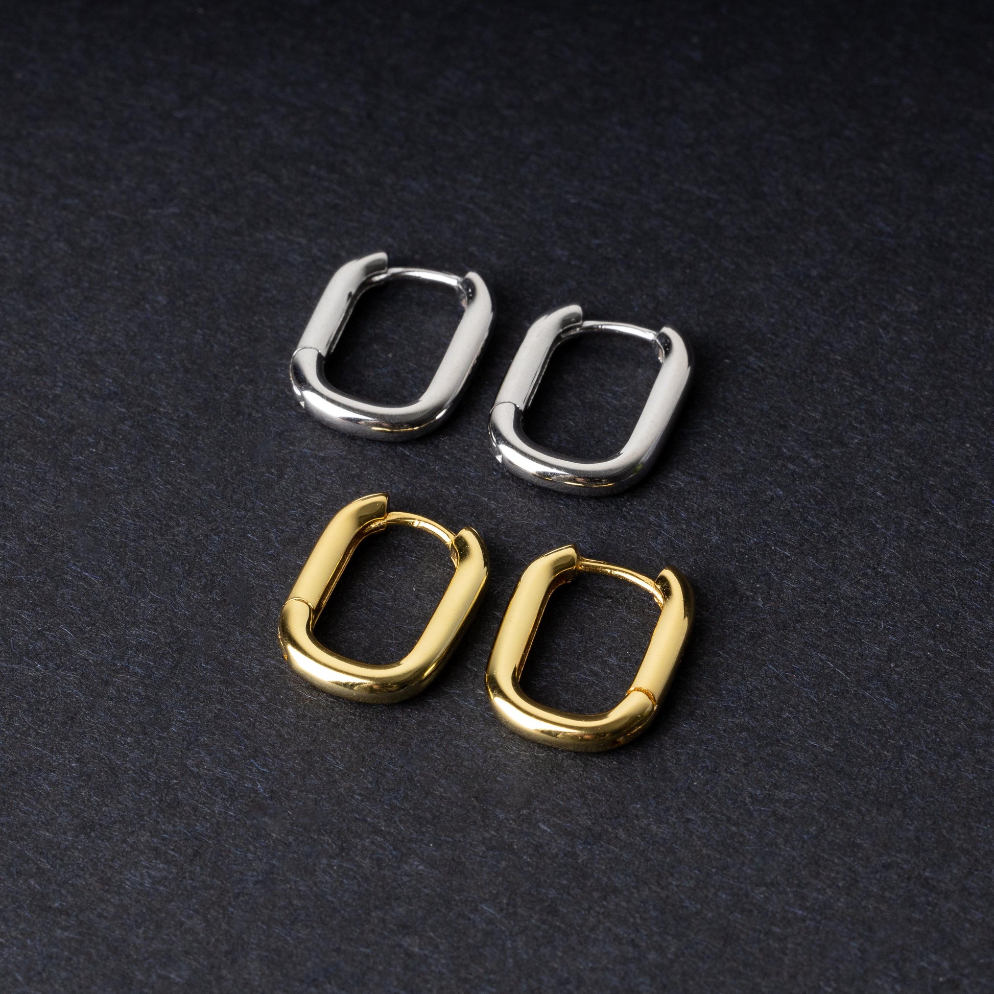 Four rectangular huggie hoop earrings made from 925 sterling silver, two in gold-tone and two in silver-tone, displayed on a dark background.