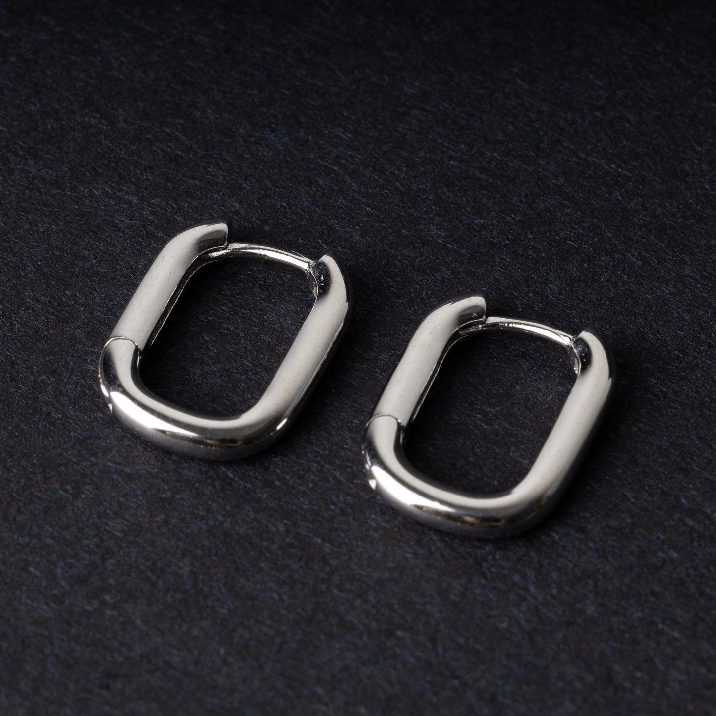 Four rectangular huggie hoop earrings made from 925 sterling silver, two in gold-tone and two in silver-tone, displayed on a dark background.
