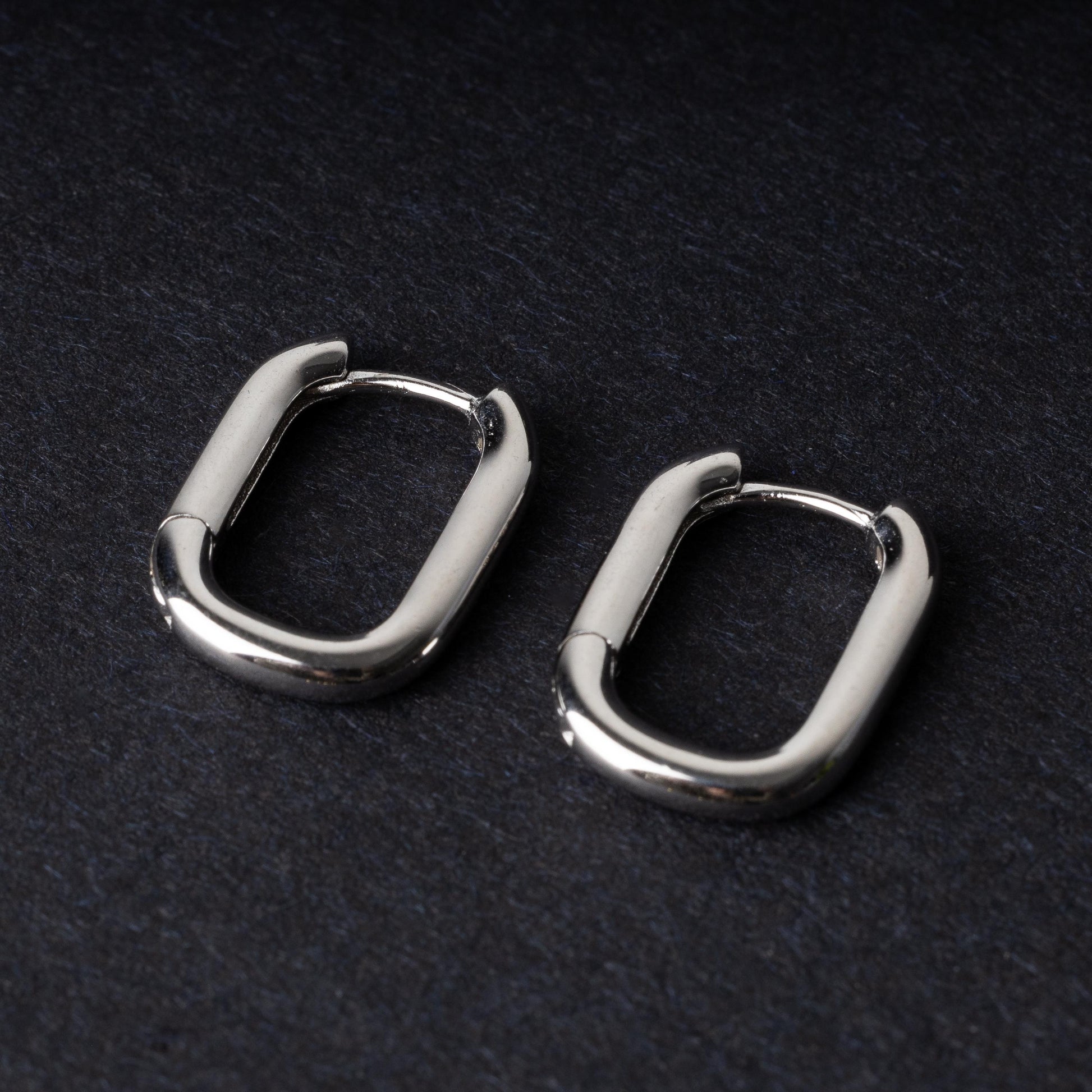 Four rectangular huggie hoop earrings made from 925 sterling silver, two in gold-tone and two in silver-tone, displayed on a dark background.