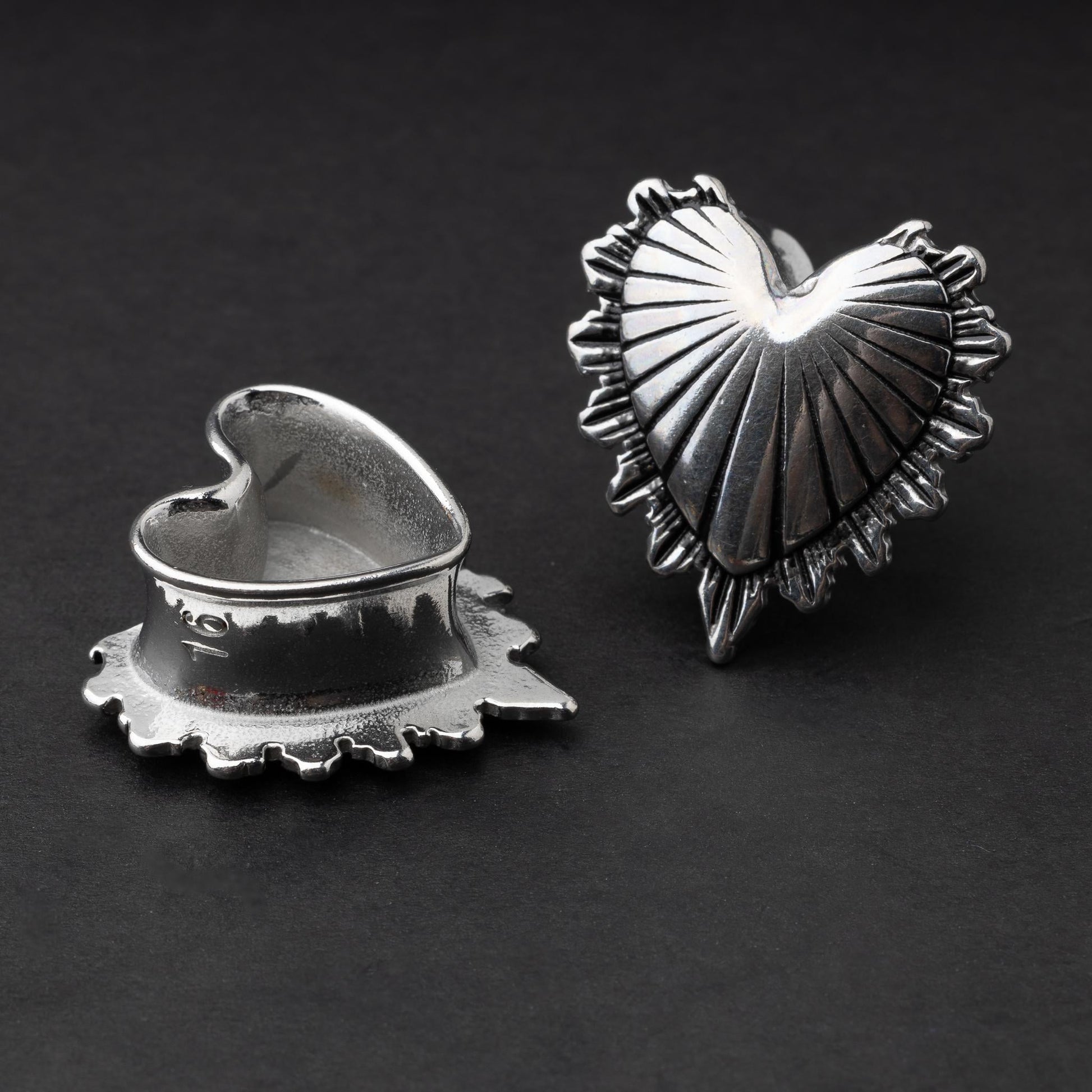 Sacred Heart plugs in gold and silver finishes, showcasing intricate 3D heart designs with a radiant pattern, displayed on a matte dark background.