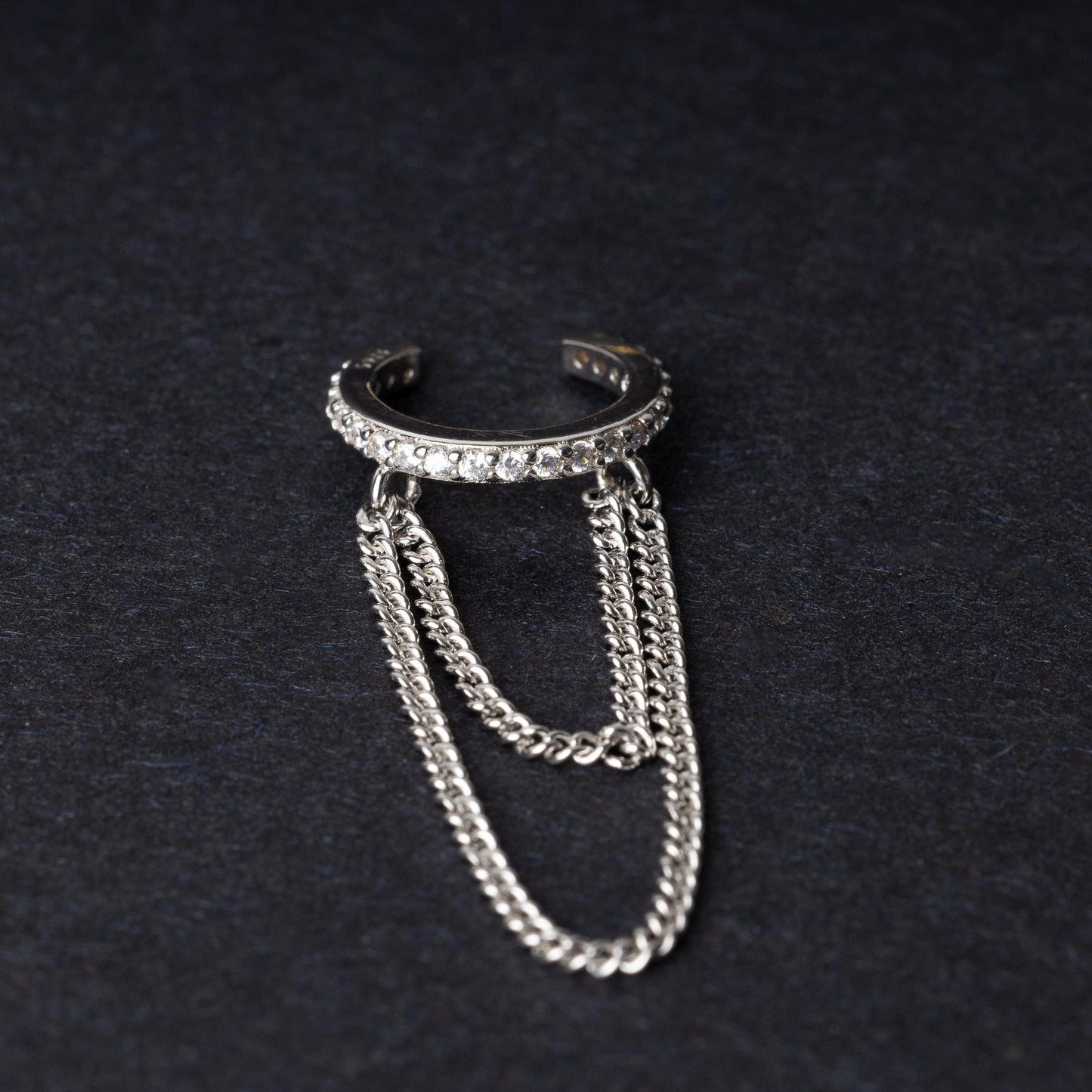 Septum clicker with double chains and gem-encrusted arc, in silver shown on a dark background.