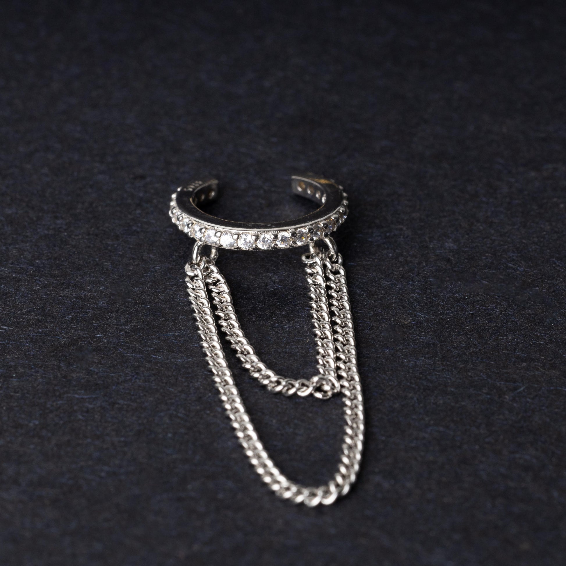 Septum clicker with double chains and gem-encrusted arc, in silver shown on a dark background.