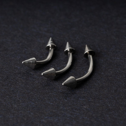 Three stainless steel curved barbells with cone-shaped ends, displayed on a dark background.