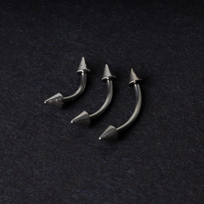 Three stainless steel curved barbells with cone-shaped ends, displayed on a dark background.