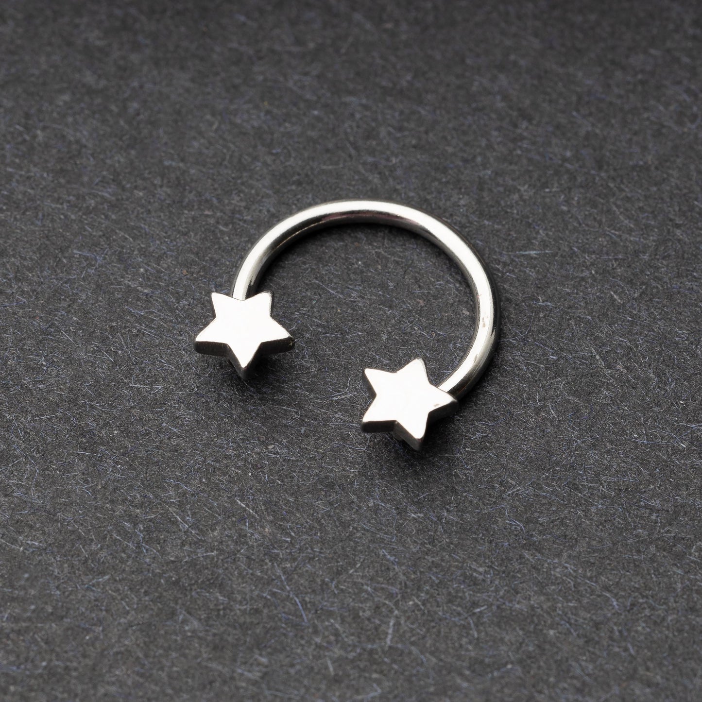 Stainless steel horseshoe hoop with star-shaped ends displayed on a dark background.