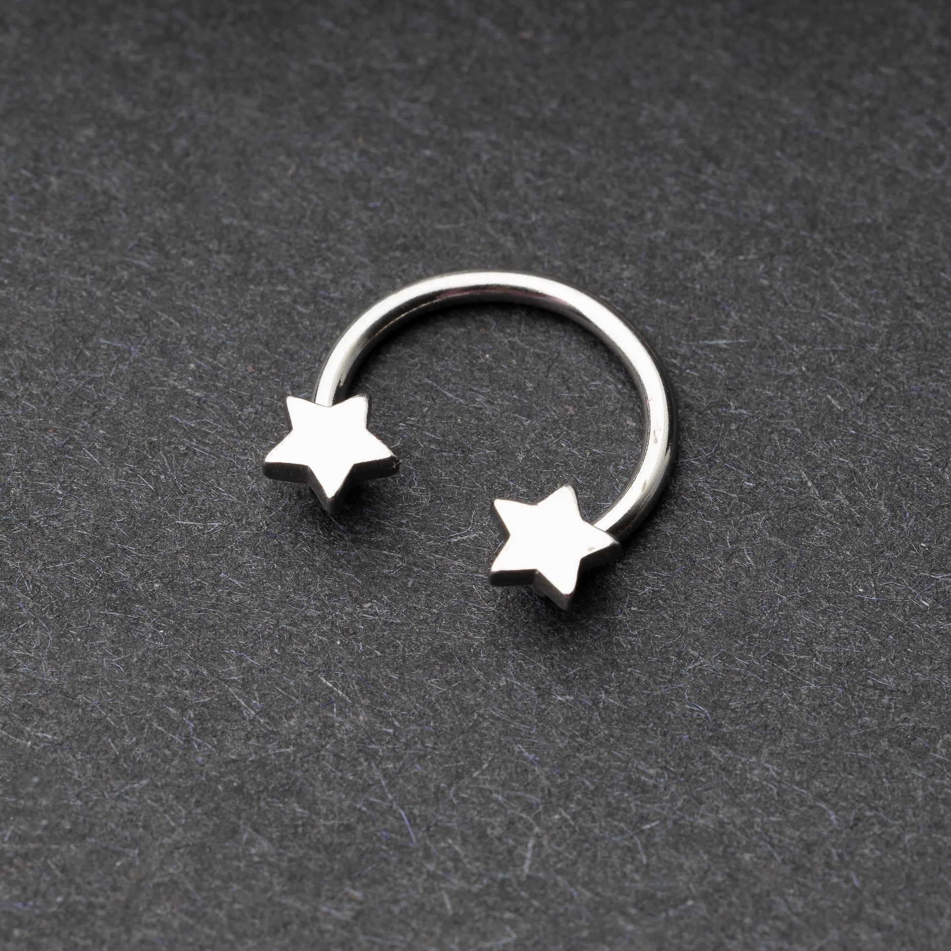 Stainless steel horseshoe hoop with star-shaped ends displayed on a dark background.