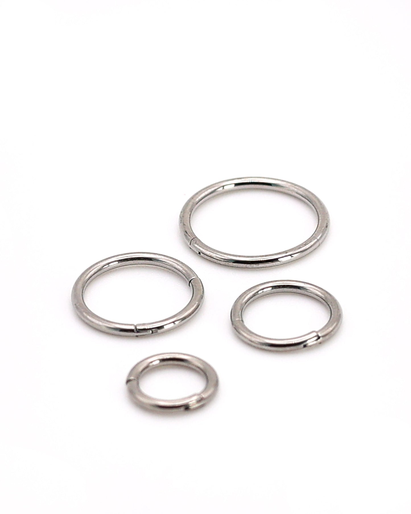 A selection of silver coloured titanium clicker hoops on a white background. 
