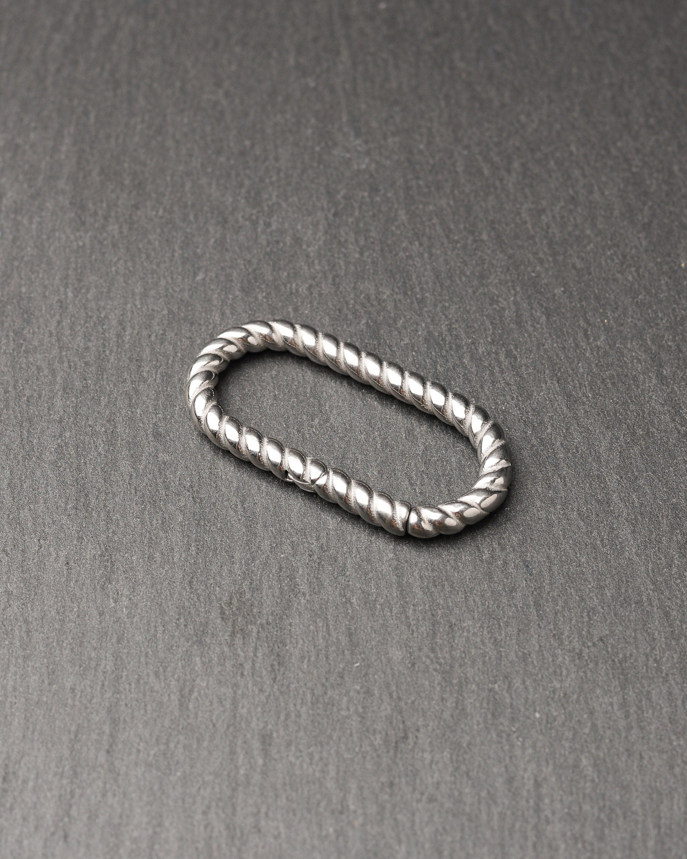 Twisted ear hangers in silver and black finishes displayed on a dark background, showcasing their rope-like design and bold style.