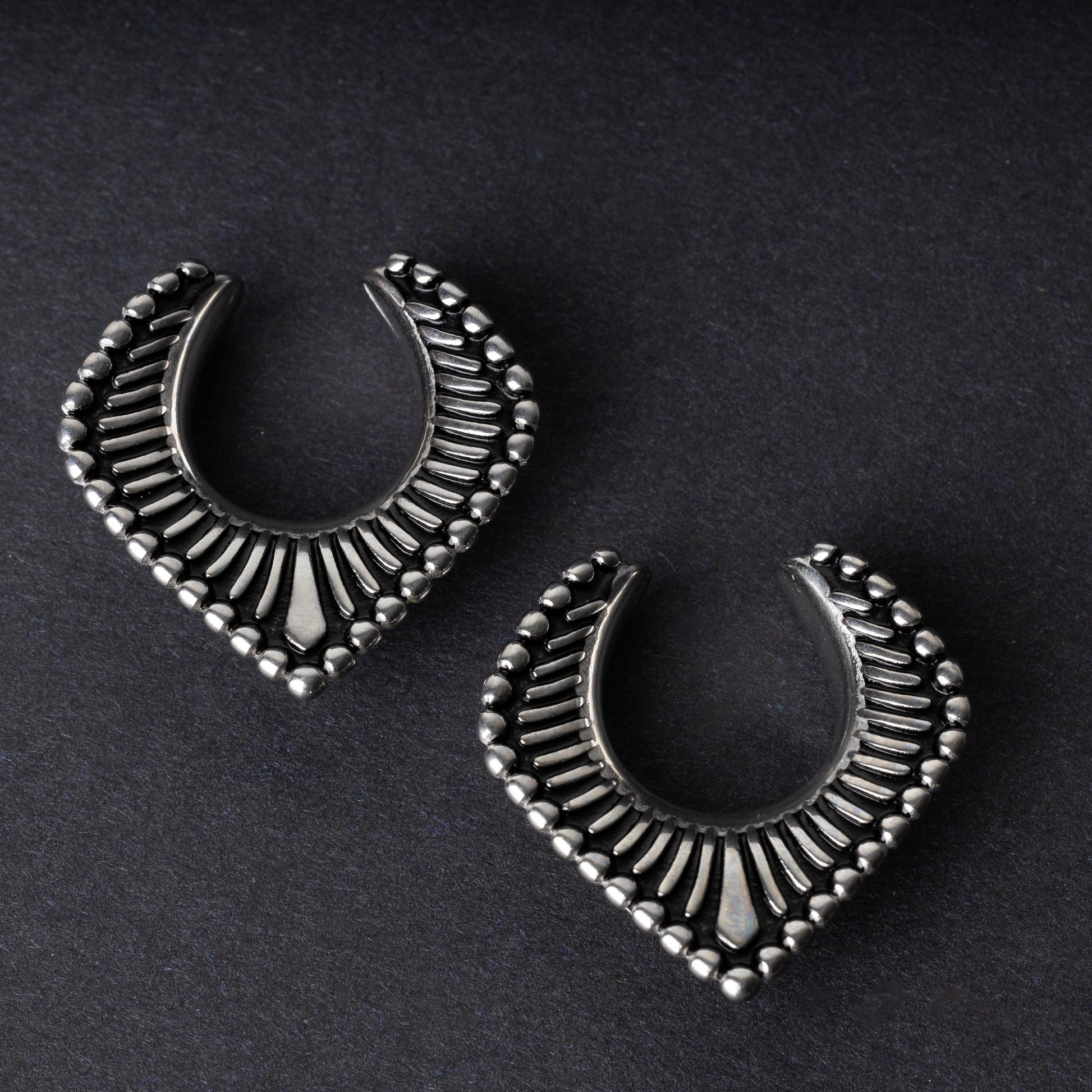 Silver saddle hangers on a dark textured background.