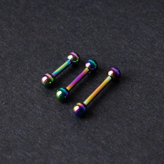Rainbow stainless steel barbells with an anodized finish on a dark background.
