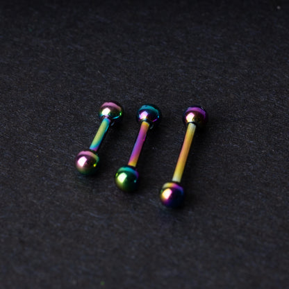 Rainbow stainless steel barbells with an anodized finish on a dark background.