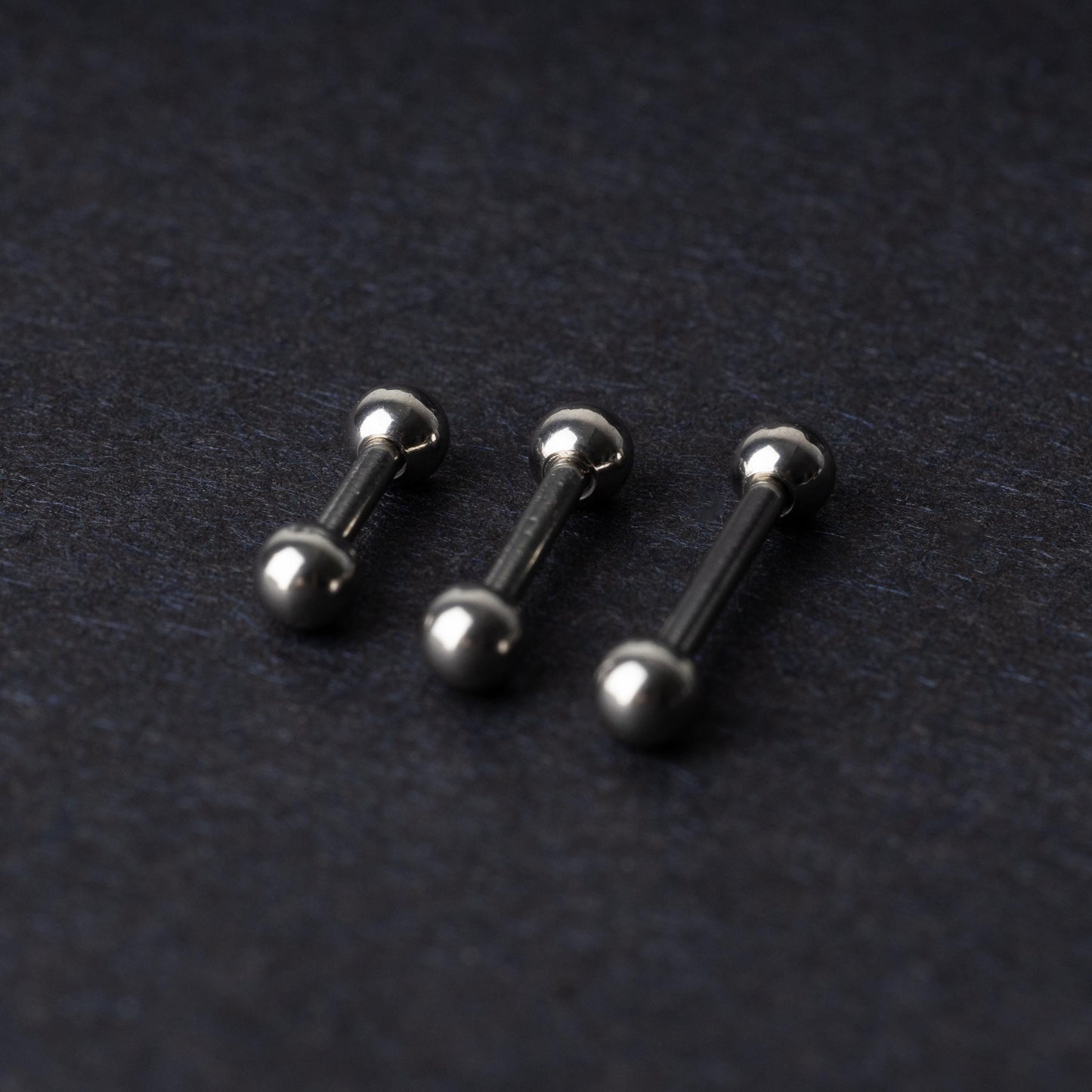 Stainless steel barbells on a dark background.