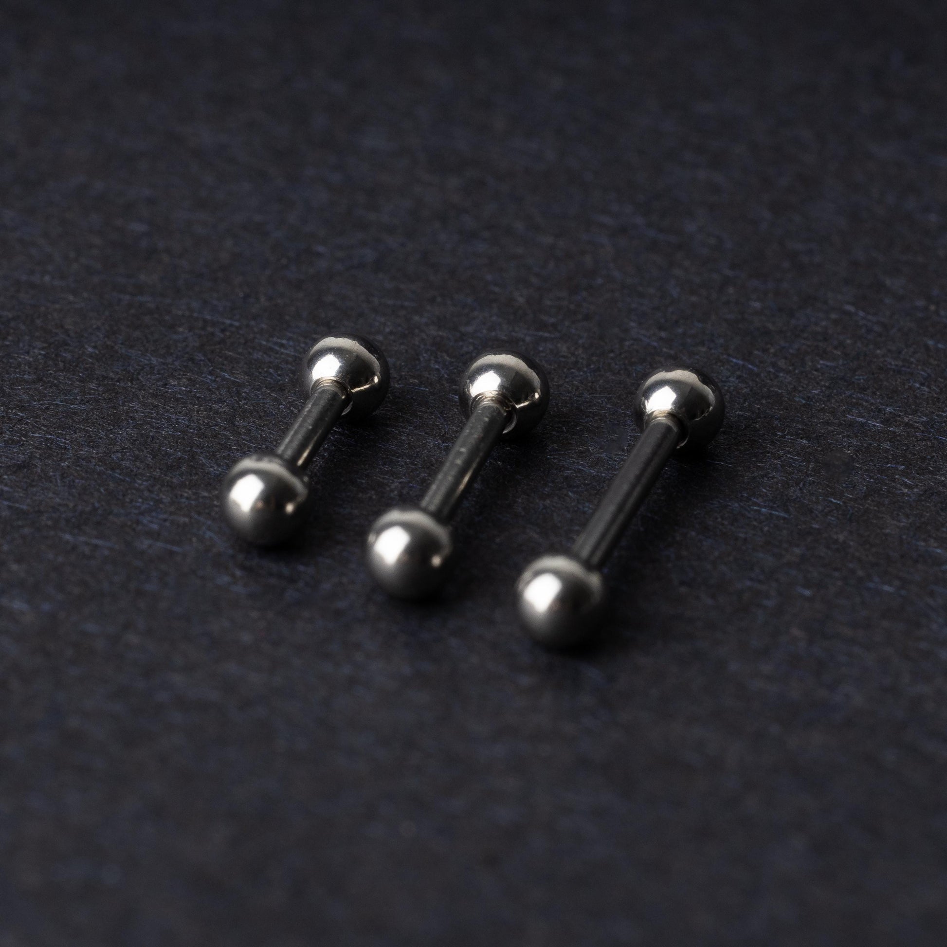 Stainless steel barbells on a dark background.