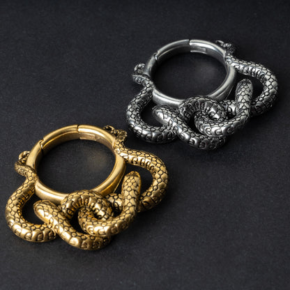 Two snake ear weights, one in polished gold and one in polished silver, featuring detailed scales and a seamless hinge closure, displayed on a dark background.

