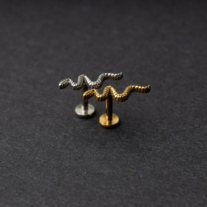 Silver and gold snake motif labrets made of stainless steel displayed on a dark background.
