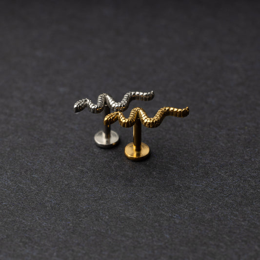 Silver and gold snake motif labrets made of stainless steel displayed on a dark background.