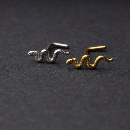 Snake-shaped nose studs in gold and silver finishes displayed on a dark background.