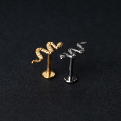 Gold-tone and silver-tone snake labret bars with intricate coiled snake designs displayed on a dark background.

