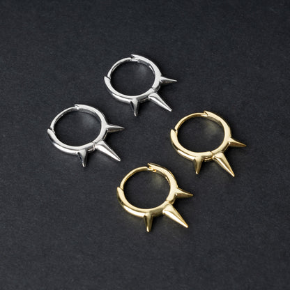 Pair of sterling silver and gold spiked clicker rings with three evenly spaced spikes, displayed on a dark textured background.