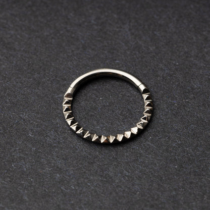 Spiked titanium clicker ring on a dark background.