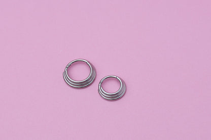 Stacked Septum Clicker in silver on a pink background.