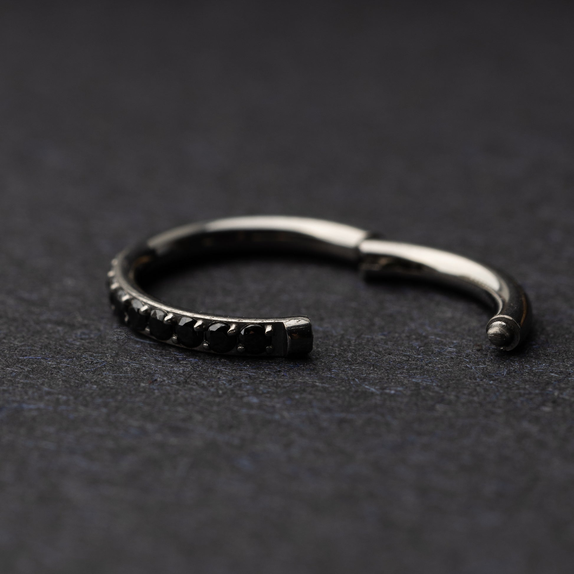 A textured stainless steel seamless ring with a polished finish, placed on a dark, textured background.