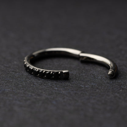 A textured stainless steel seamless ring with a polished finish, placed on a dark, textured background.