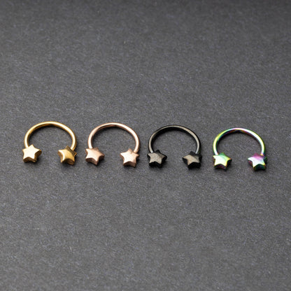 Four stainless steel horseshoe hoops with star-shaped ends in gold, rose gold, black, and rainbow finishes displayed on a dark background.