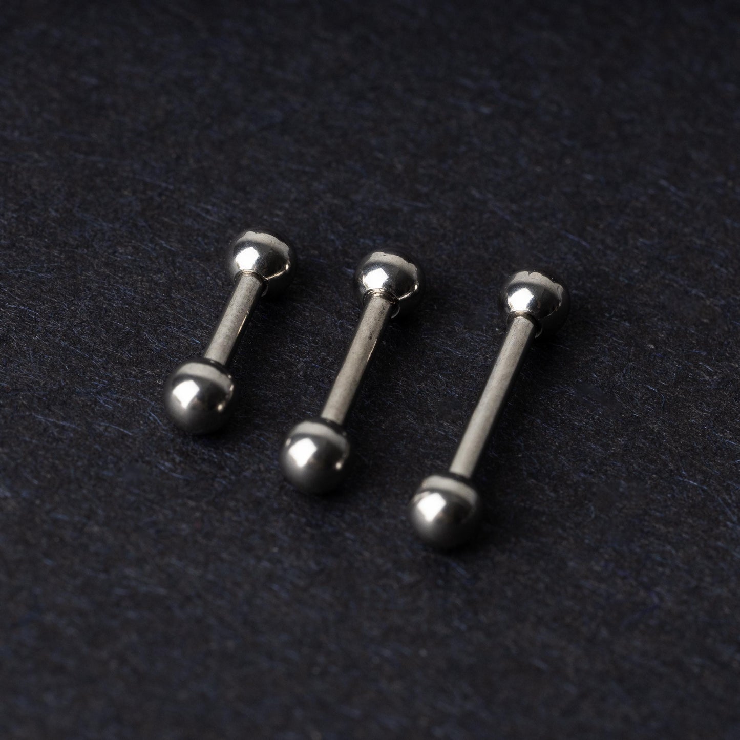 Stainless steel barbells on a dark background.