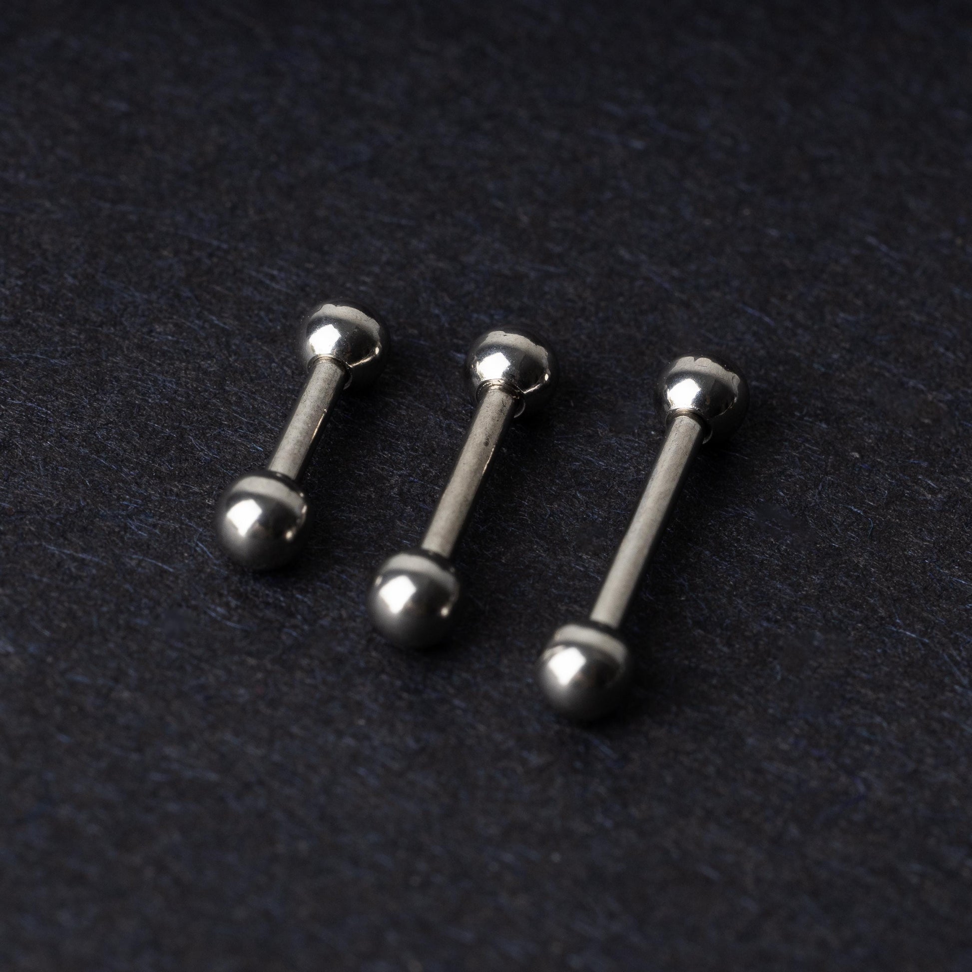 Stainless steel barbells on a dark background.