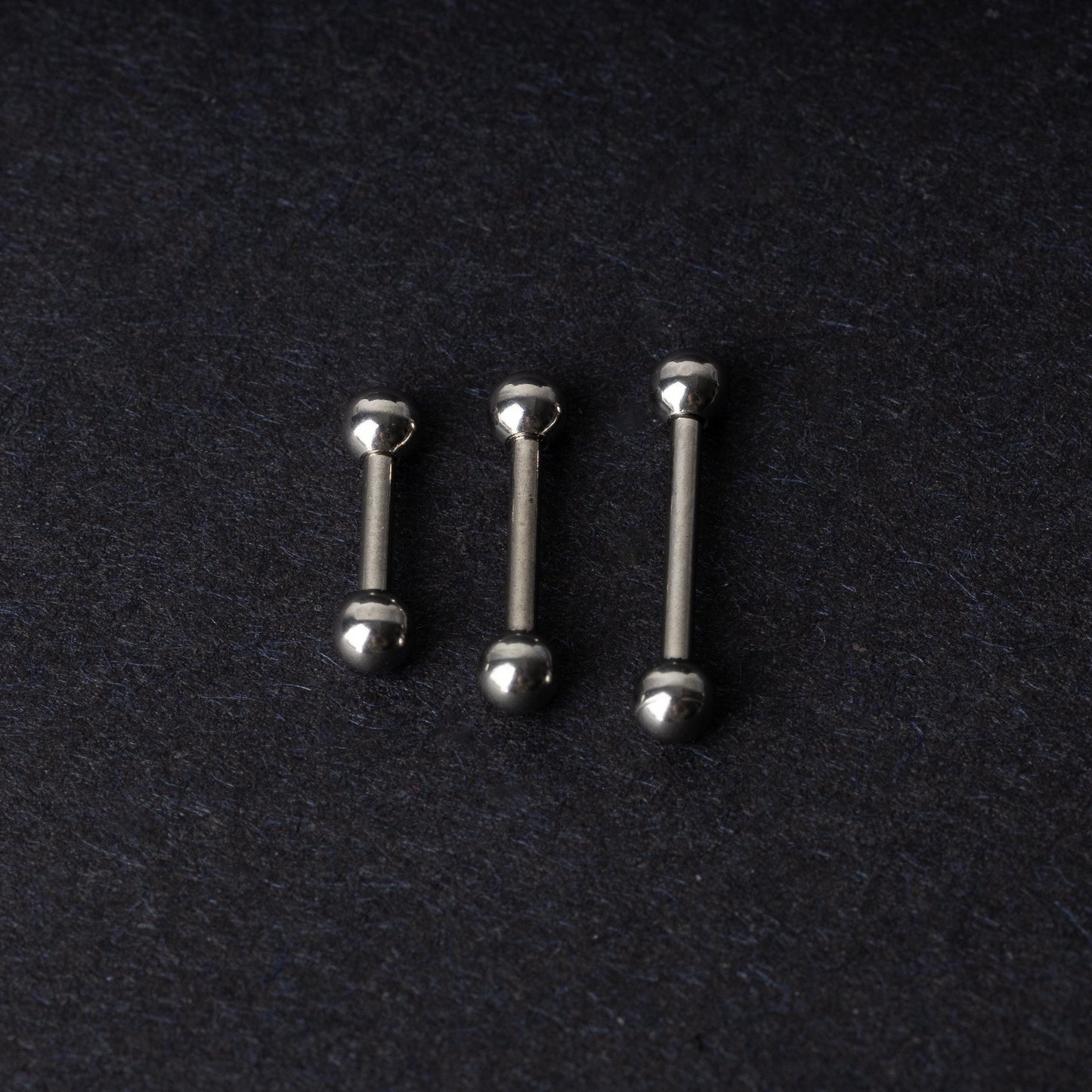 Stainless steel barbells on a dark background.