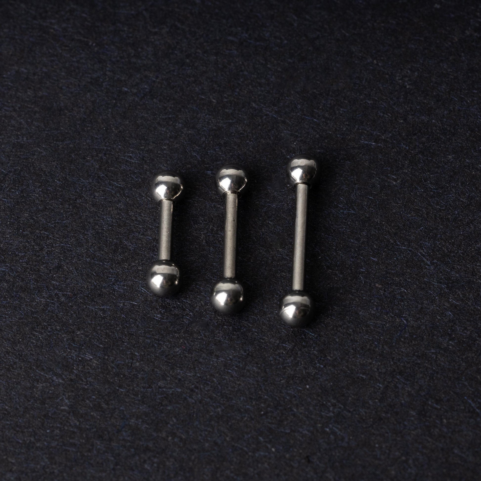 Stainless steel barbells on a dark background.