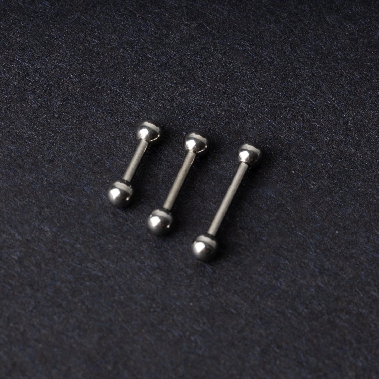 Stainless steel barbells on a dark background.