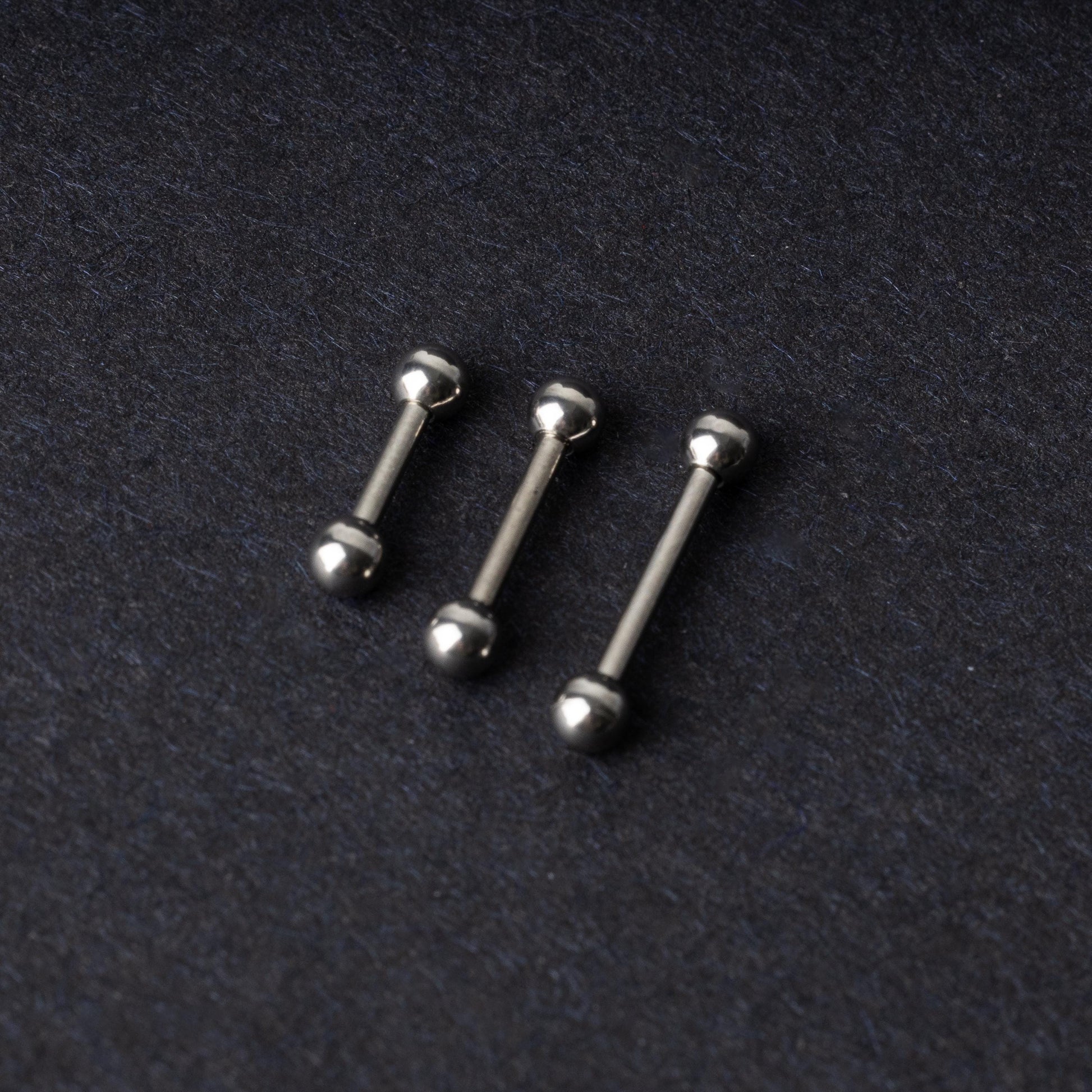 Stainless steel barbells on a dark background.