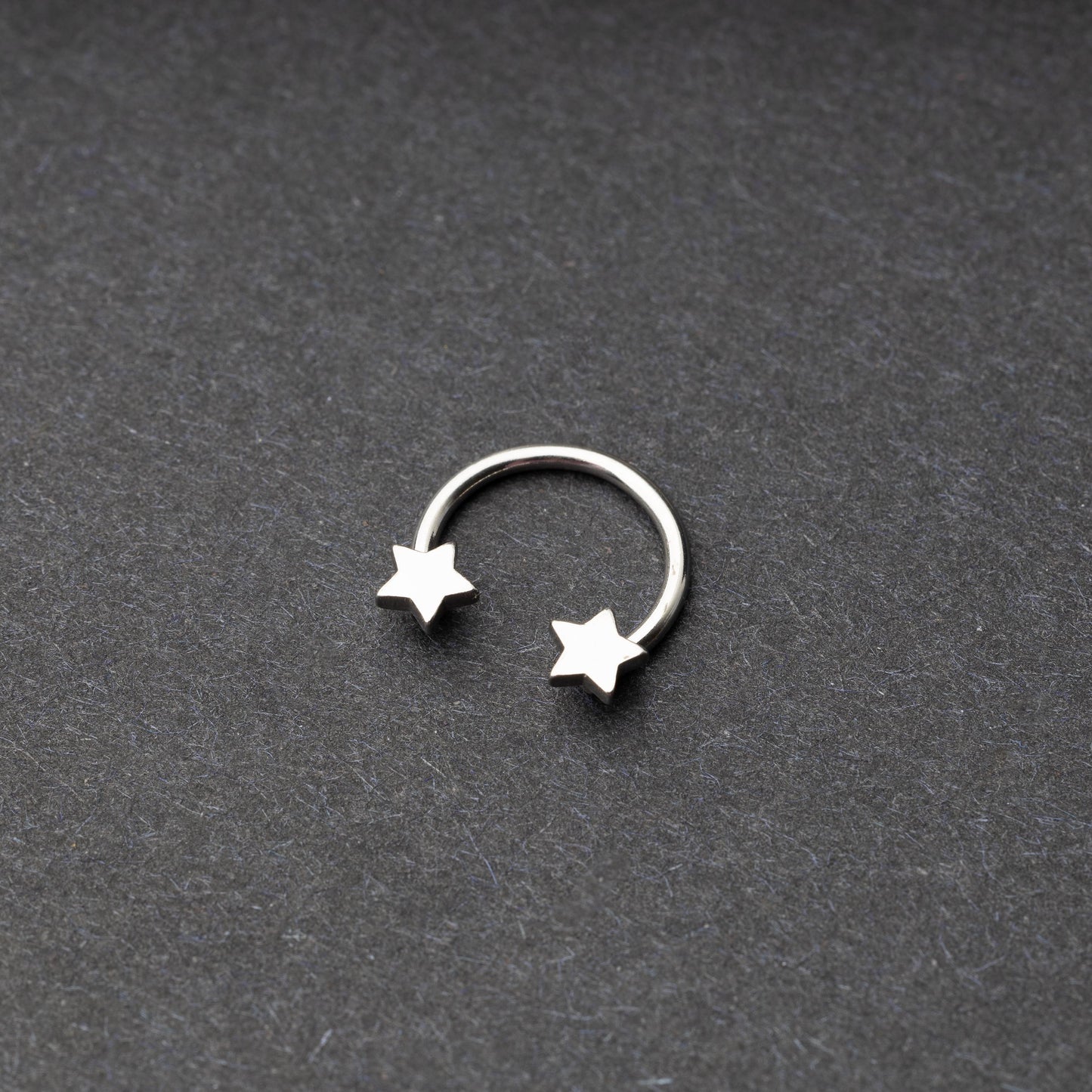 Stainless steel horseshoe hoop with star-shaped ends displayed on a dark background.