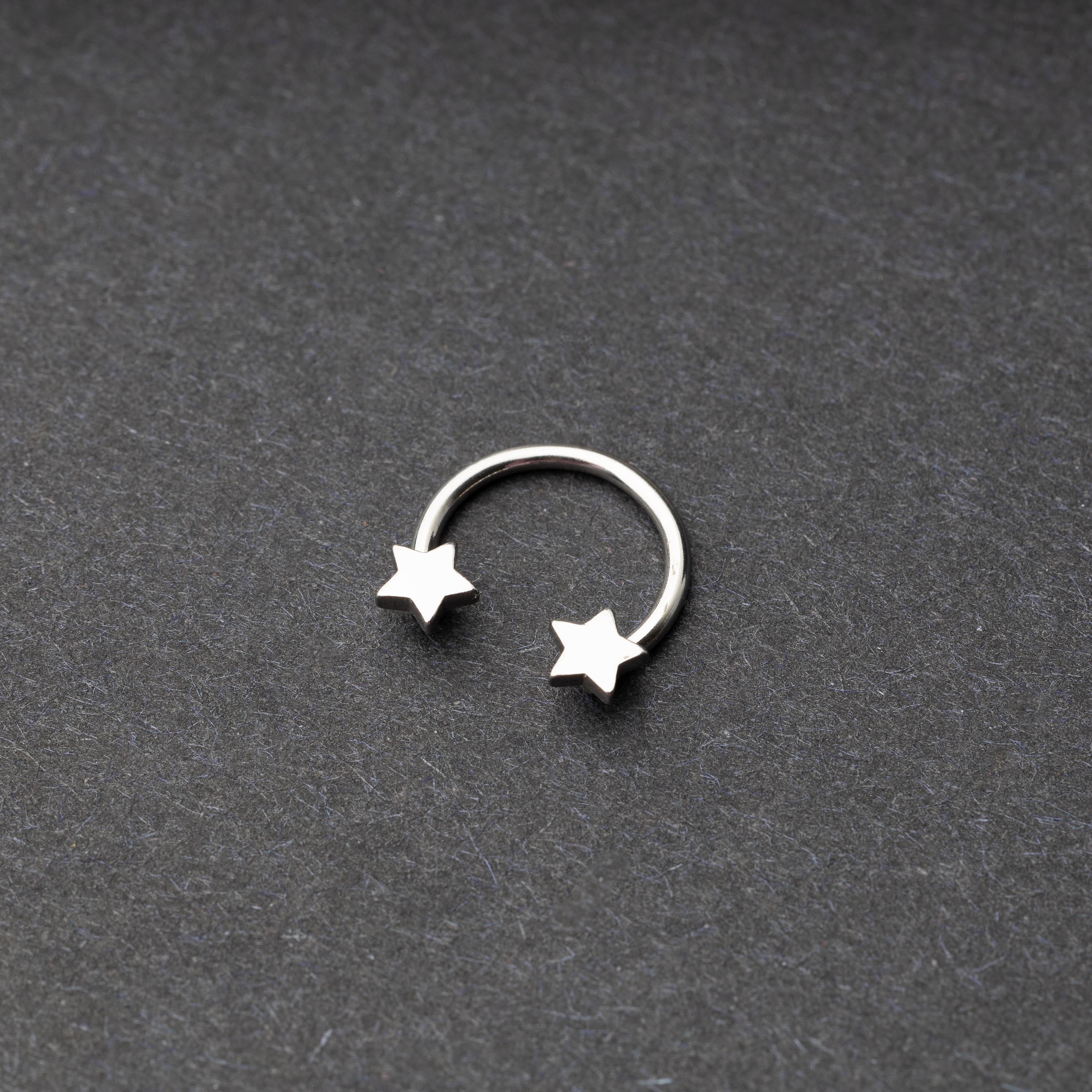 Stainless steel horseshoe hoop with star-shaped ends displayed on a dark background.
