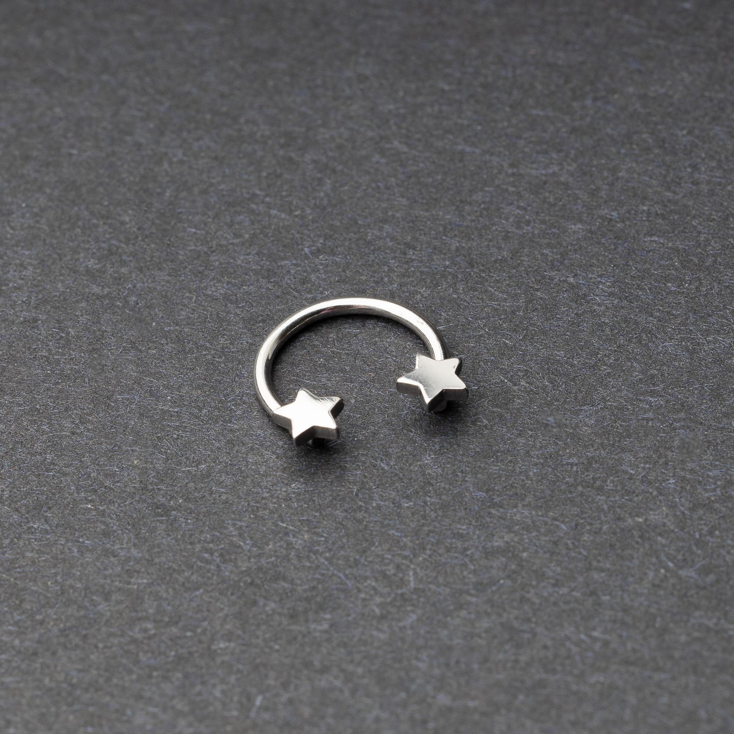 Stainless steel horseshoe hoop with star-shaped ends displayed on a dark background.