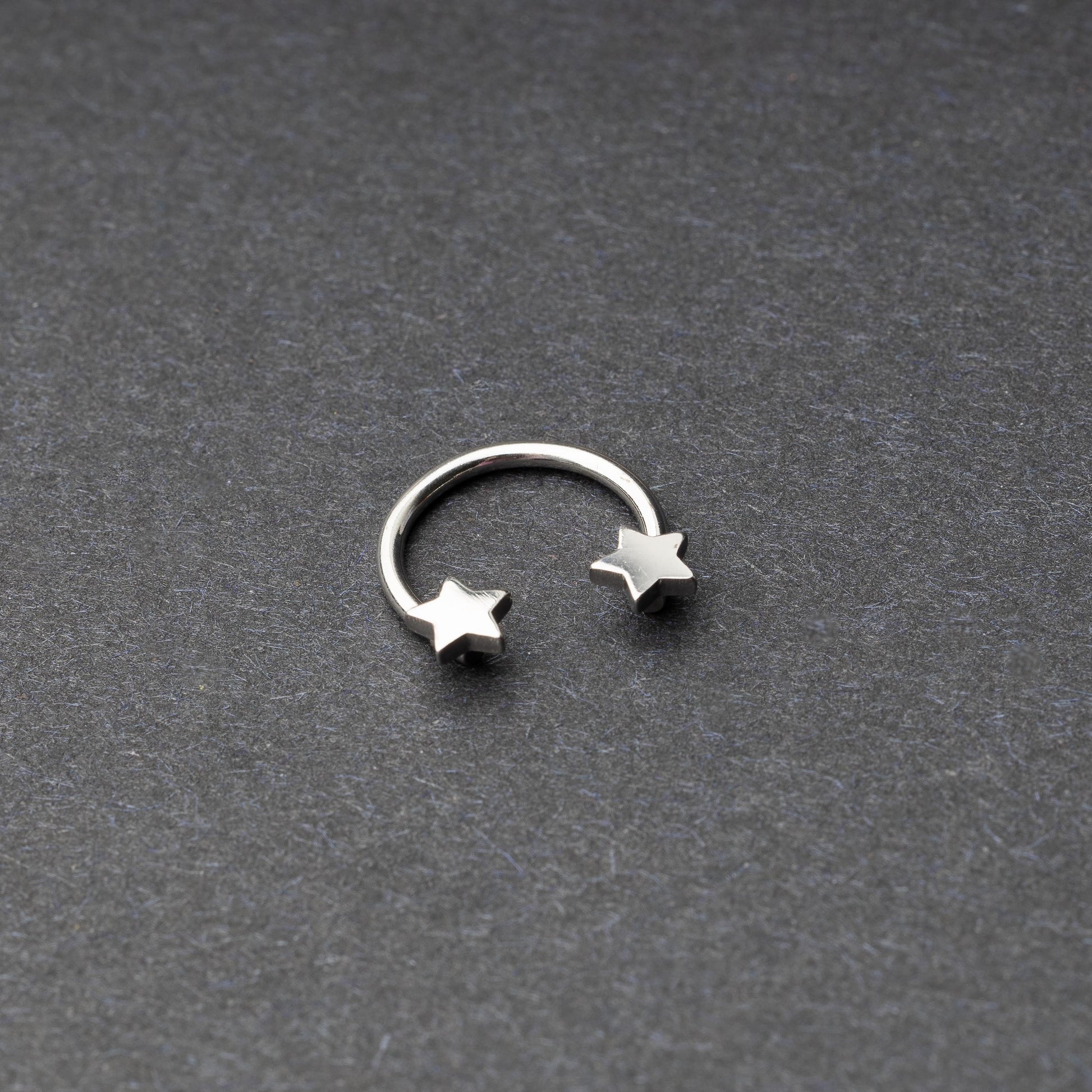 Stainless steel horseshoe hoop with star-shaped ends displayed on a dark background.