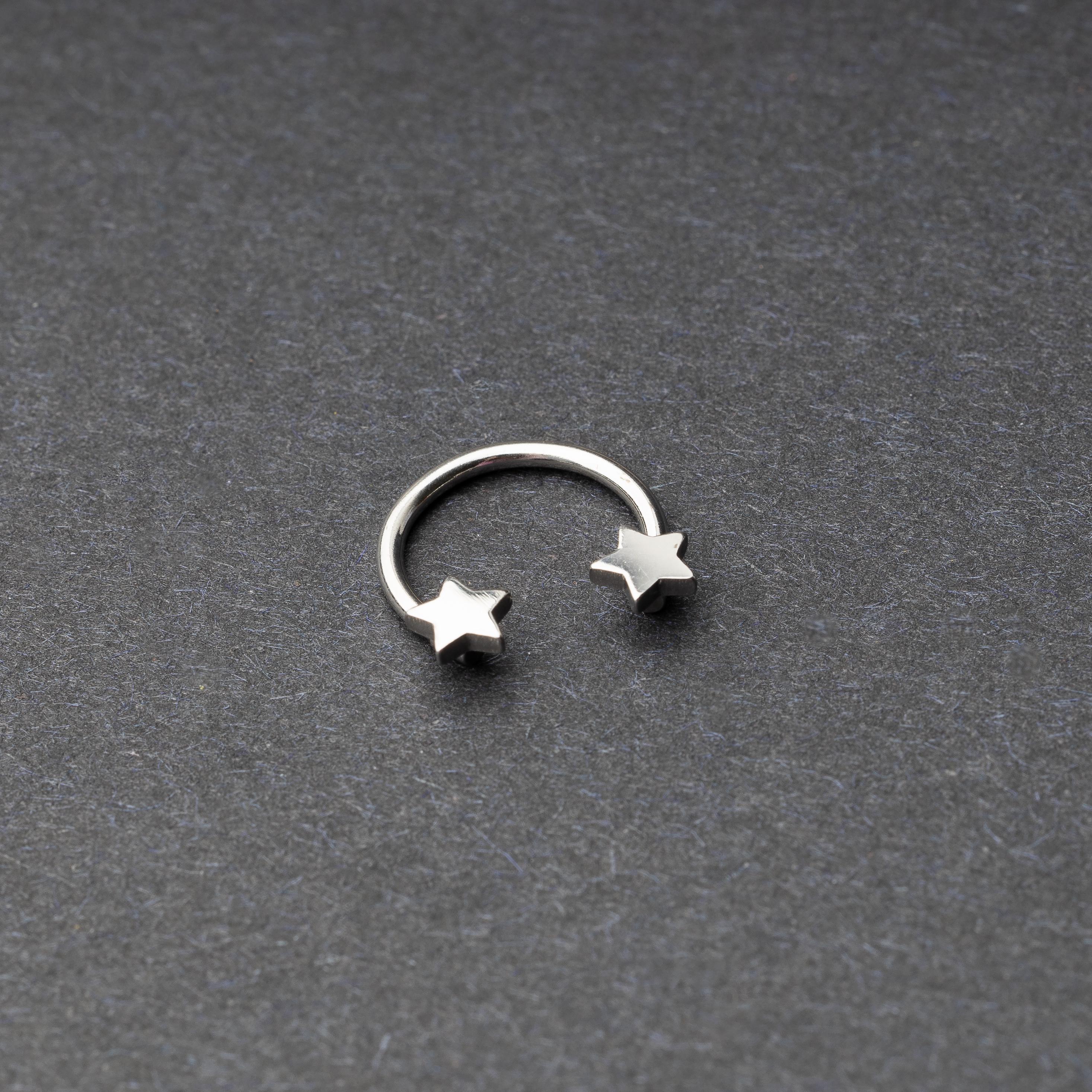 Stainless steel horseshoe hoop with star-shaped ends displayed on a dark background.