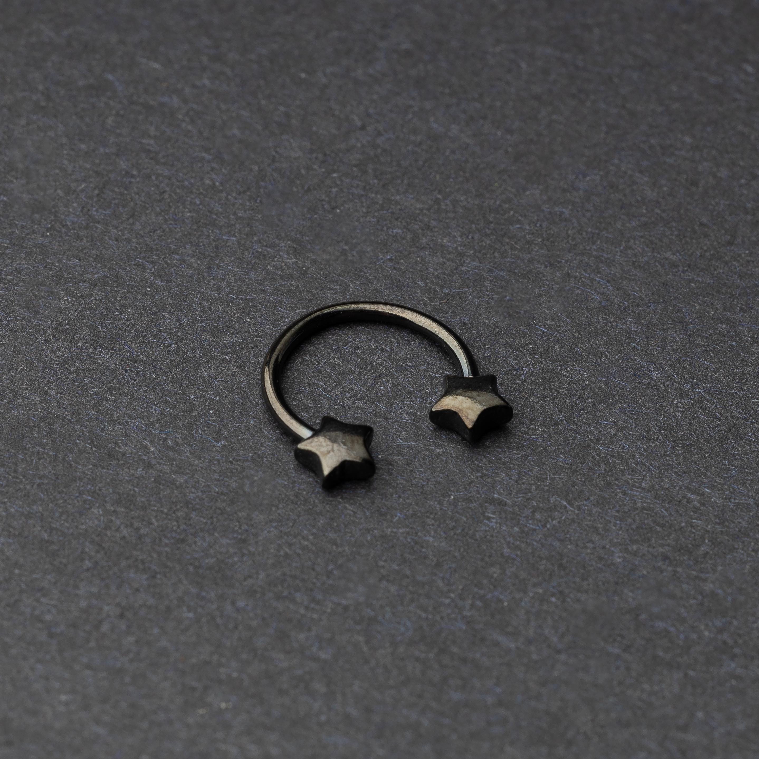 Stainless steel horseshoe hoop with star-shaped ends in black, displayed on a dark background.