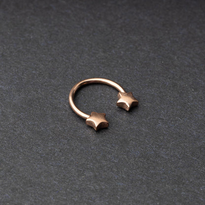 Stainless steel horseshoe hoop with star-shaped ends in rose gold, displayed on a dark background.